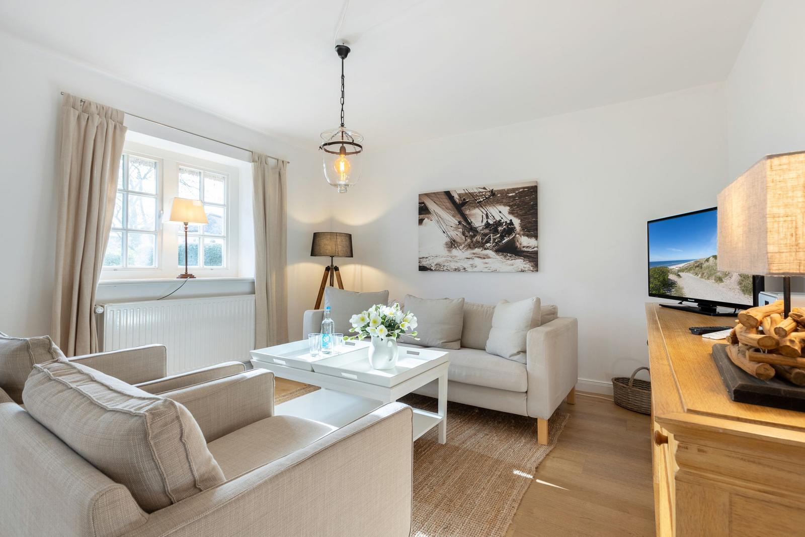 Wohnzimmer mit Sofa, Tisch und Fernseher an der Wand.