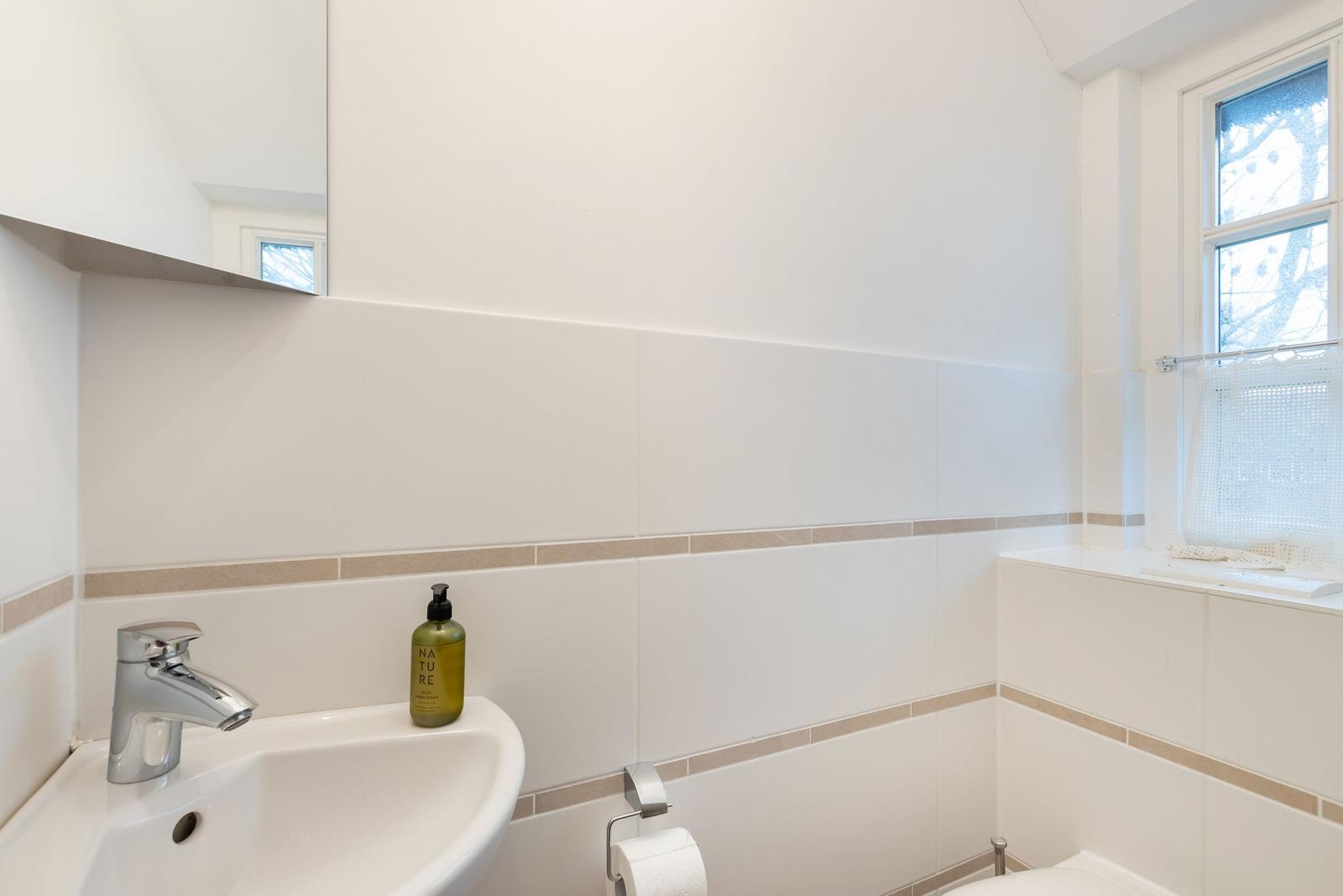 Badezimmer mit Waschbecken, Spiegel und Fenster