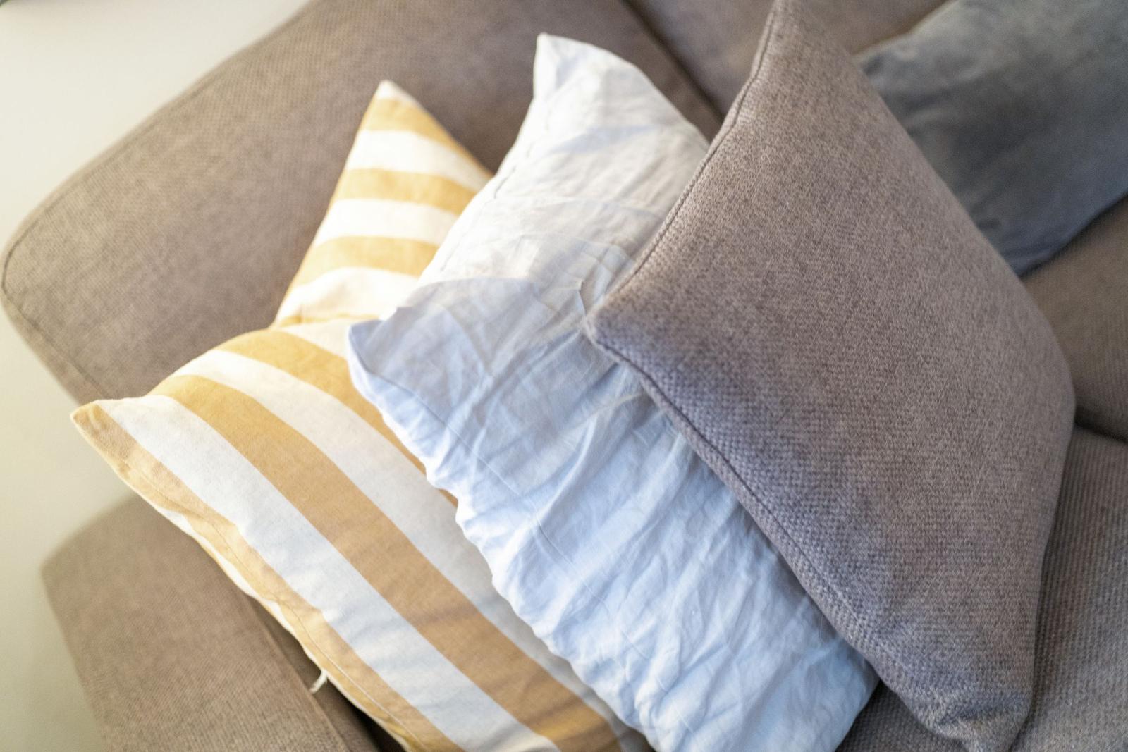 Graue Couch mit Kissen in Gelb-Weiß-Streifen und Hellblau.