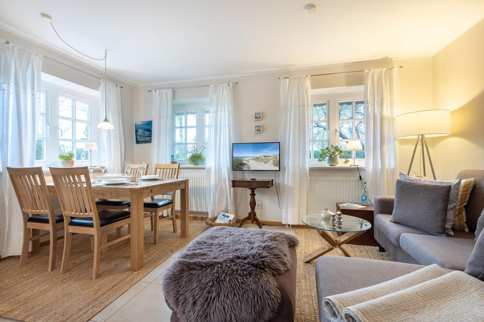 Wohn- und Essbereich mit Sofa, Esstisch und Fernseher.