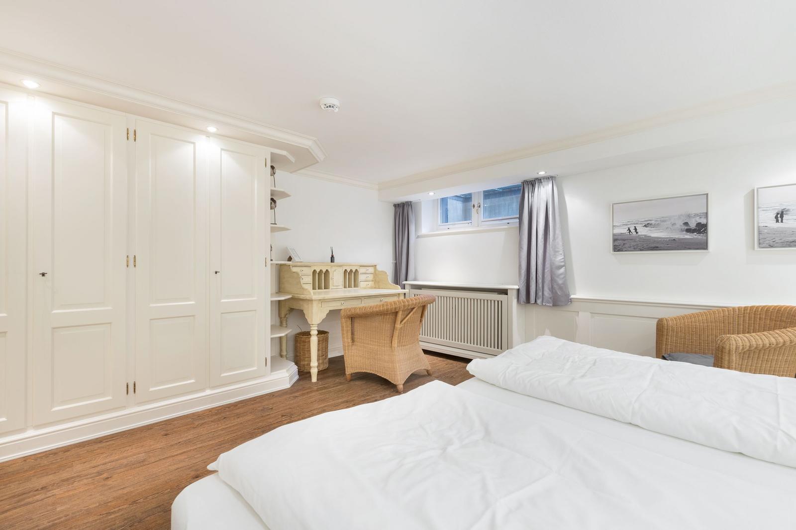 Schlafzimmer mit Bett, Schreibtisch und Kleiderschrank.
