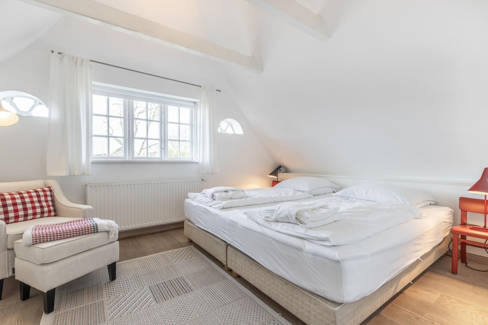Bedroom with double bed, window, and seating area.