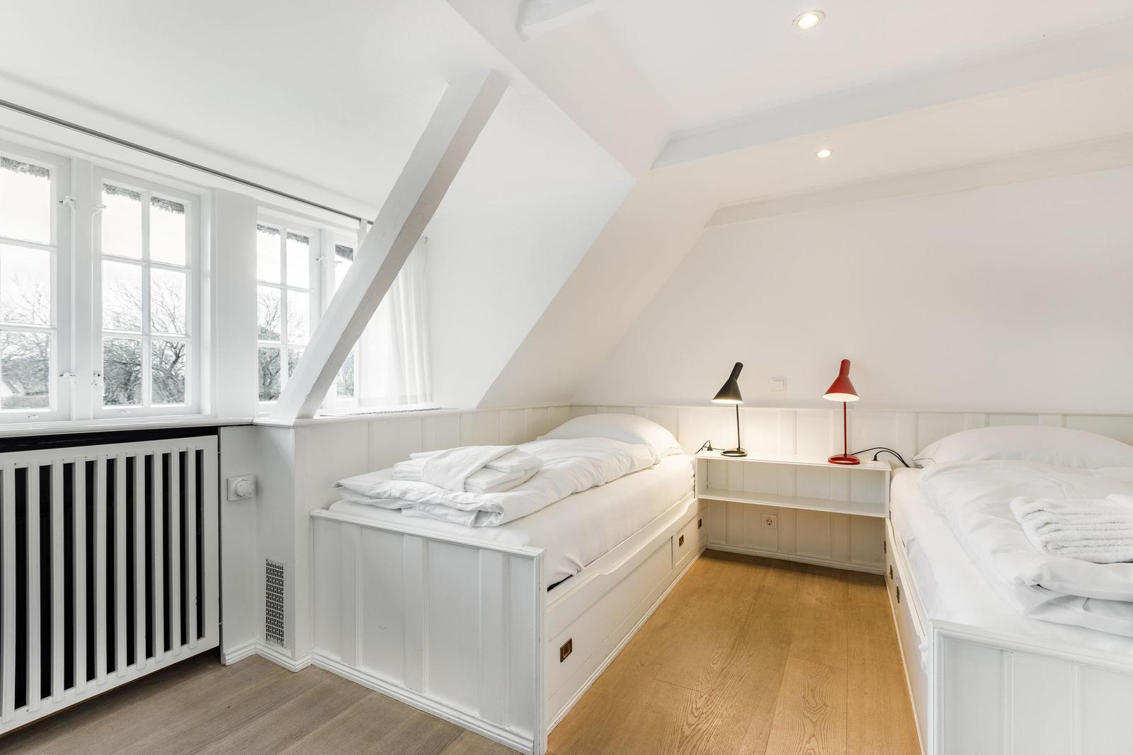 Room with two beds, windows, and wooden floor.