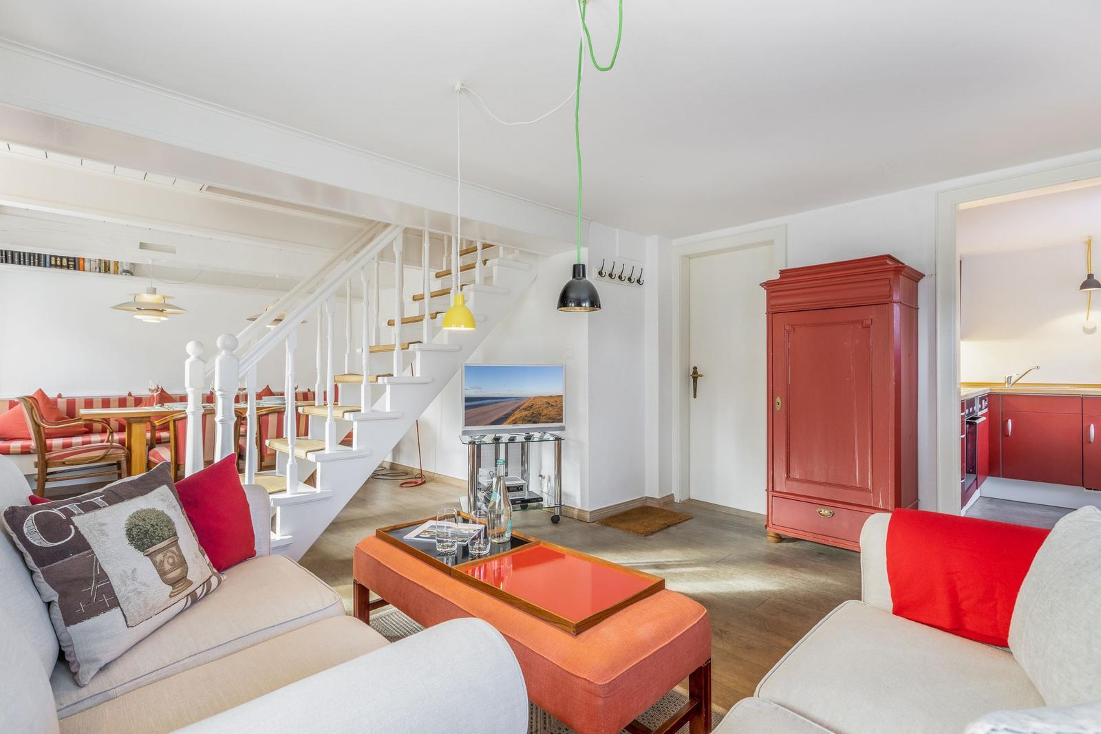 Living area with red cabinet, staircase, and sofa with cushions.