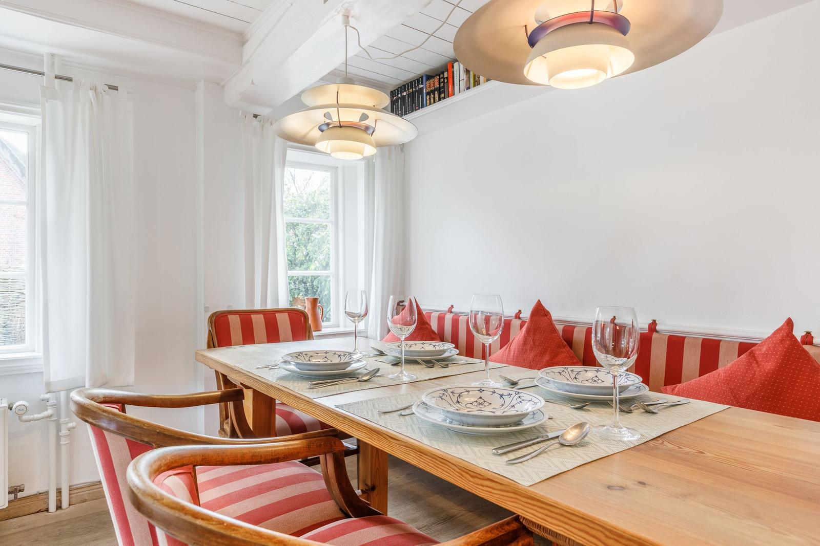 Dining room with wooden table, striped cushions, and modern ceiling lights.