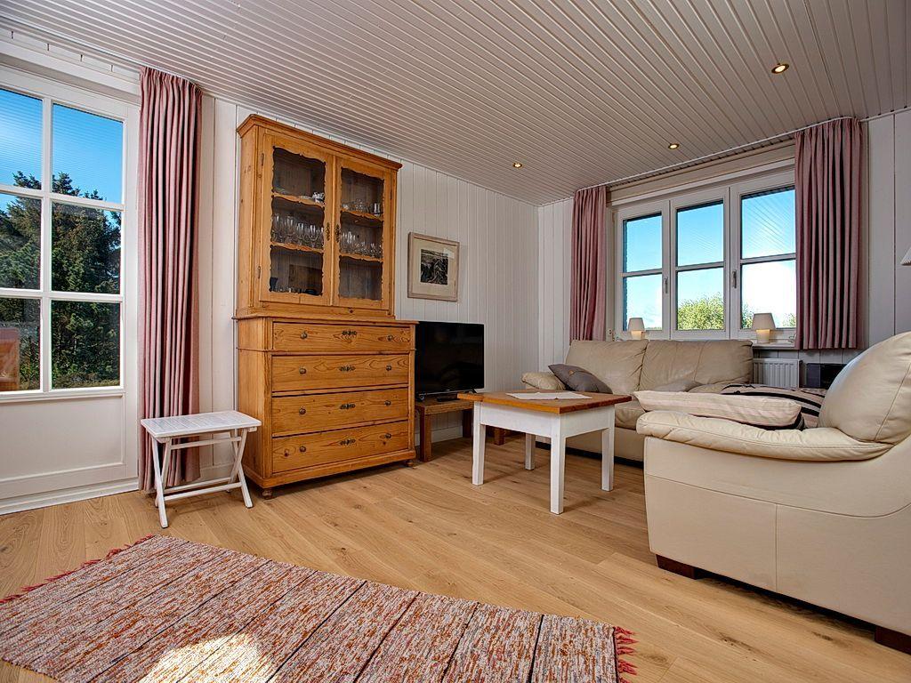 Wohnzimmer mit Holzfußboden, Sofa, Fernseher und Holzschrank.