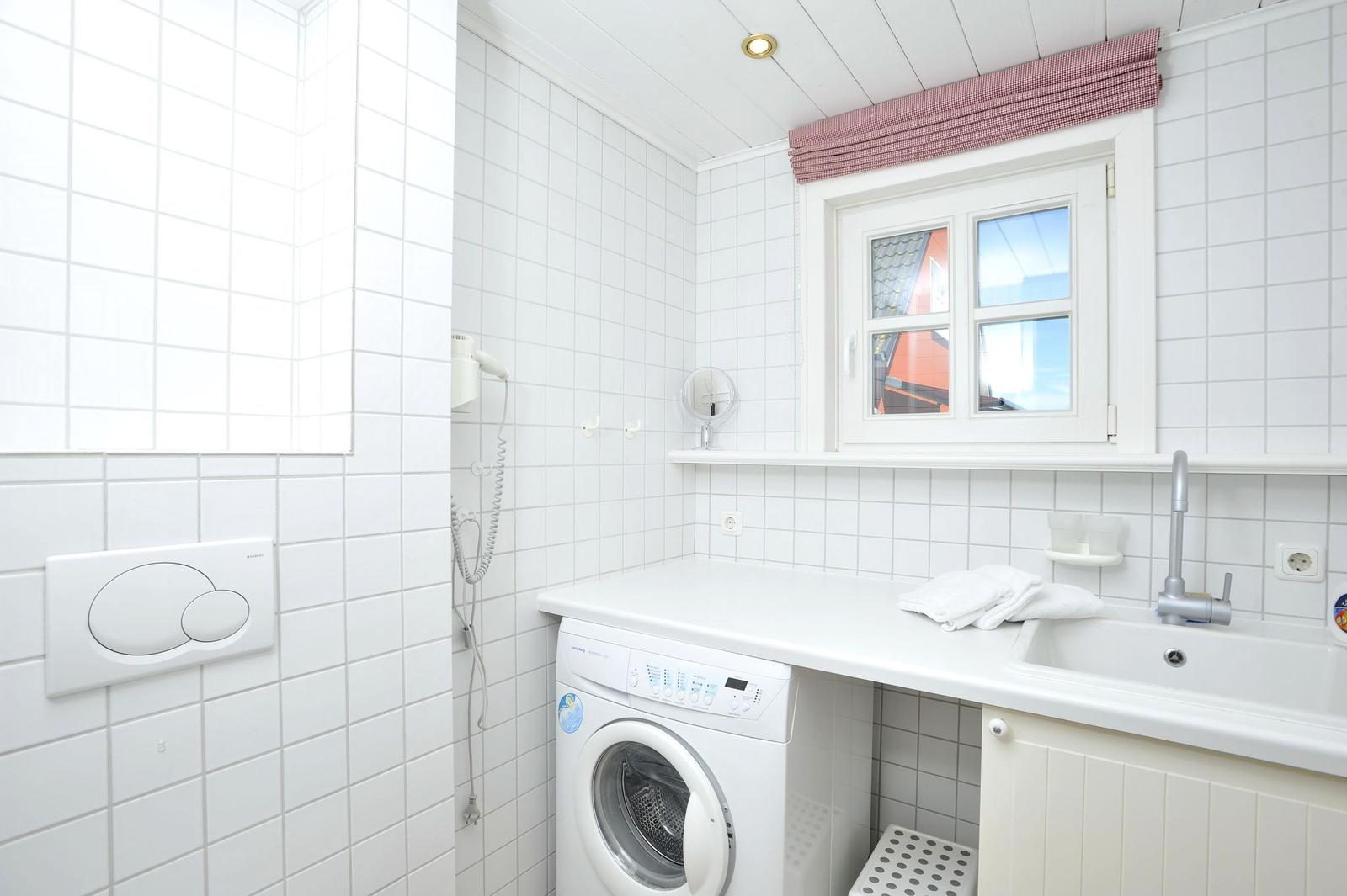 Waschraum mit Waschmaschine, Spüle und Fenster