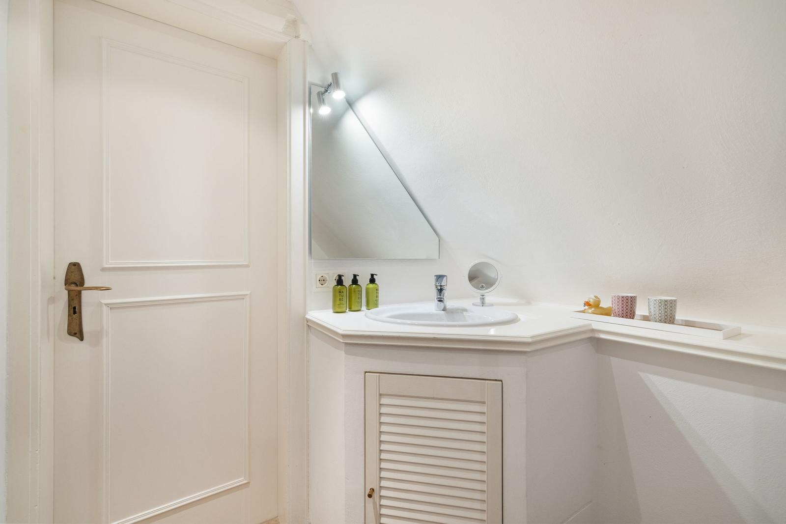 Bathroom with sink, mirror, and shower under sloped ceiling