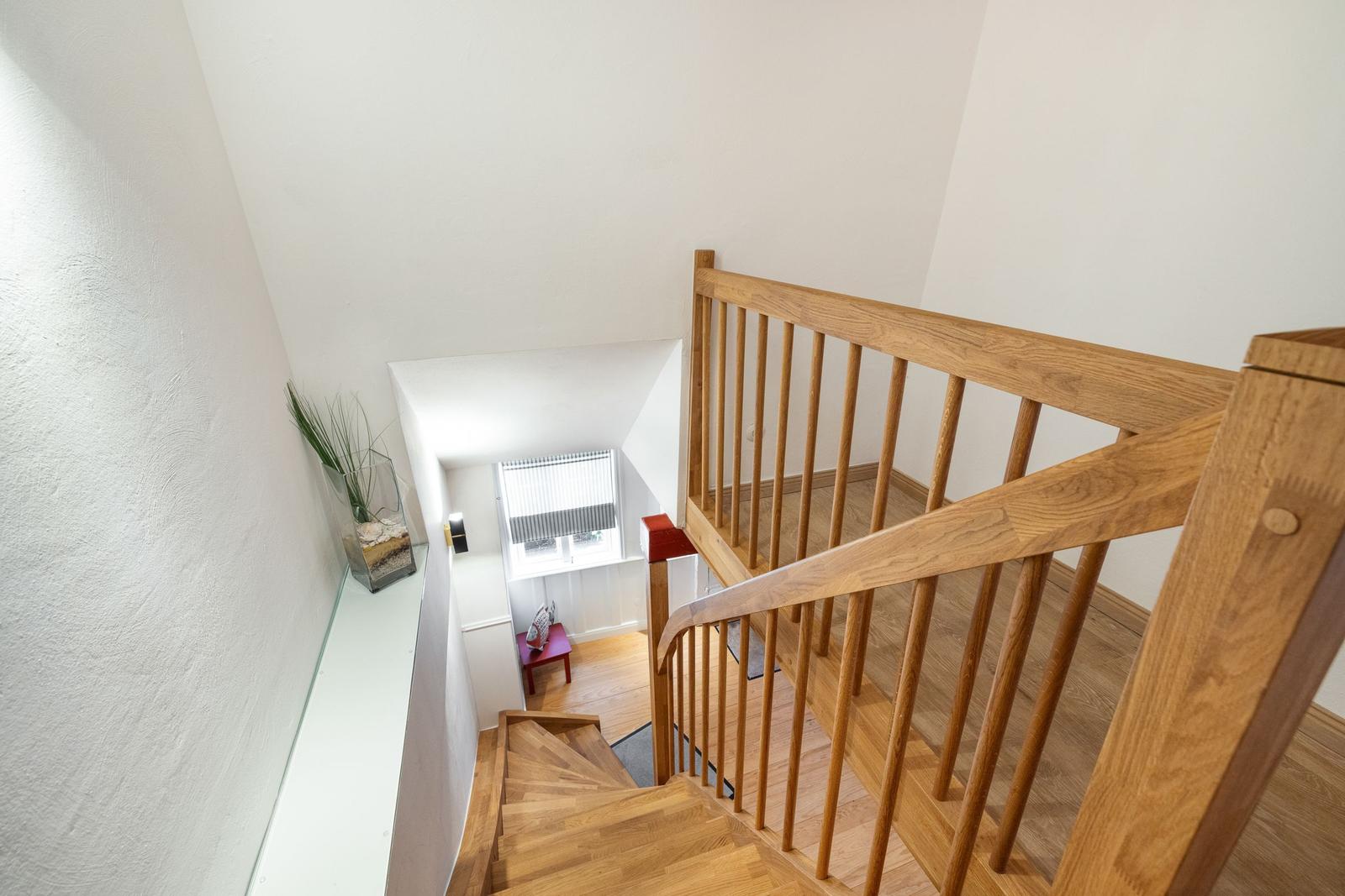 Wooden staircase with handrail and view into the lower room.