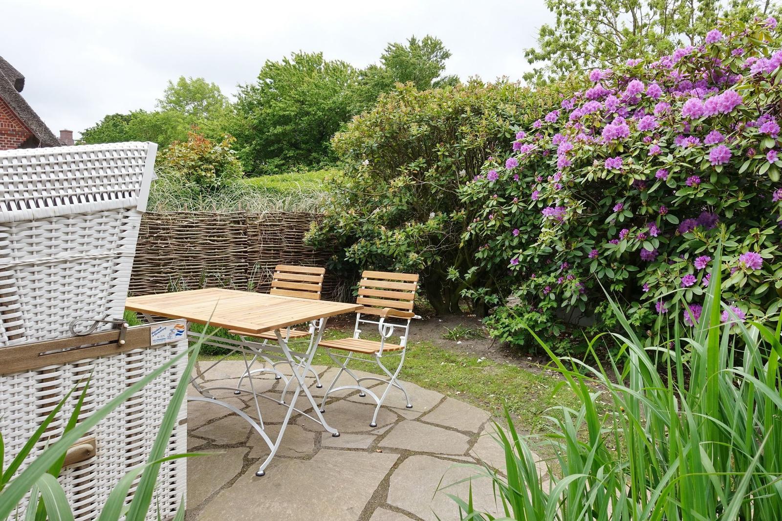 Terrace with table, two chairs, and blooming shrub