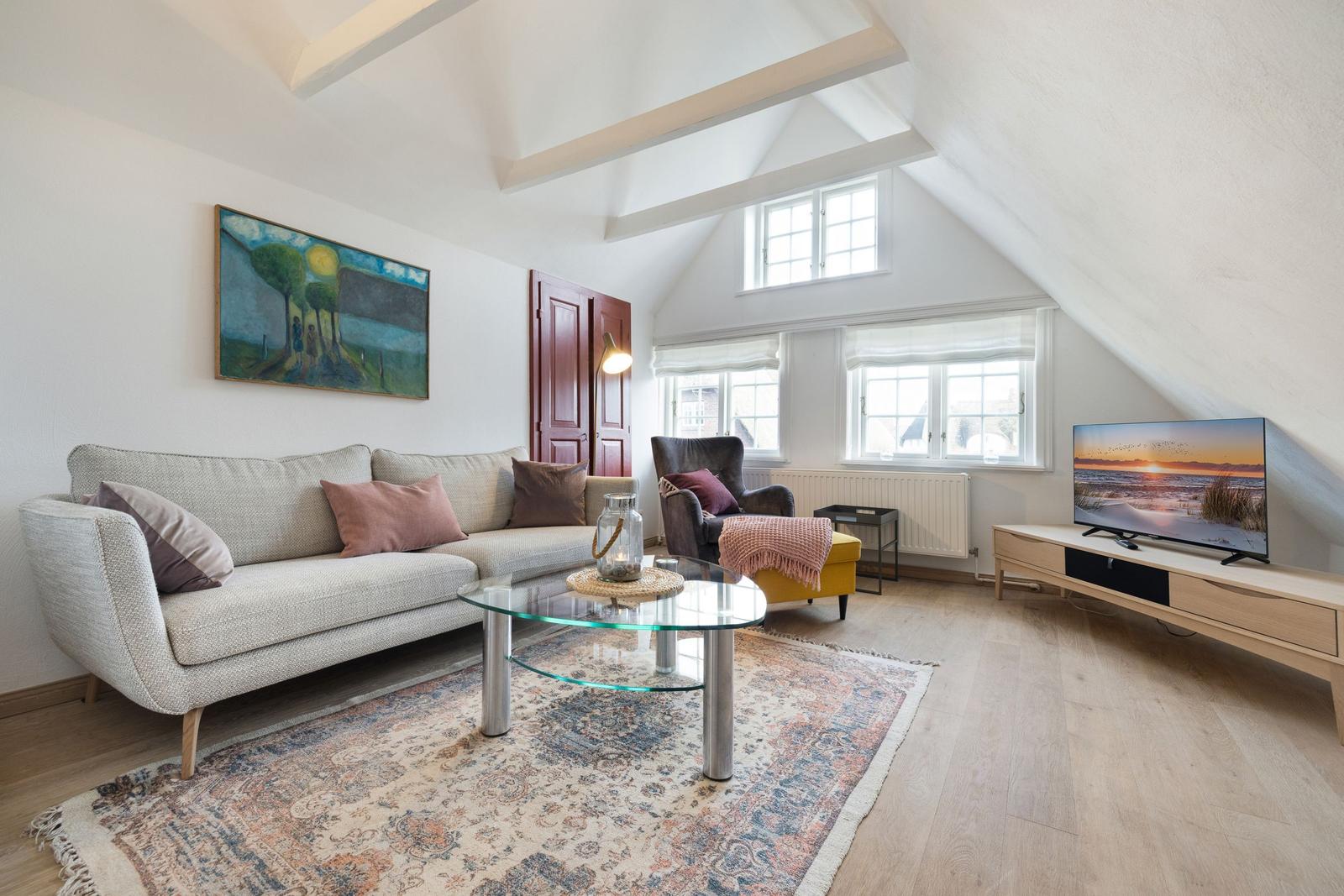 Living room with sofa, coffee table, and TV under wooden beam ceiling.