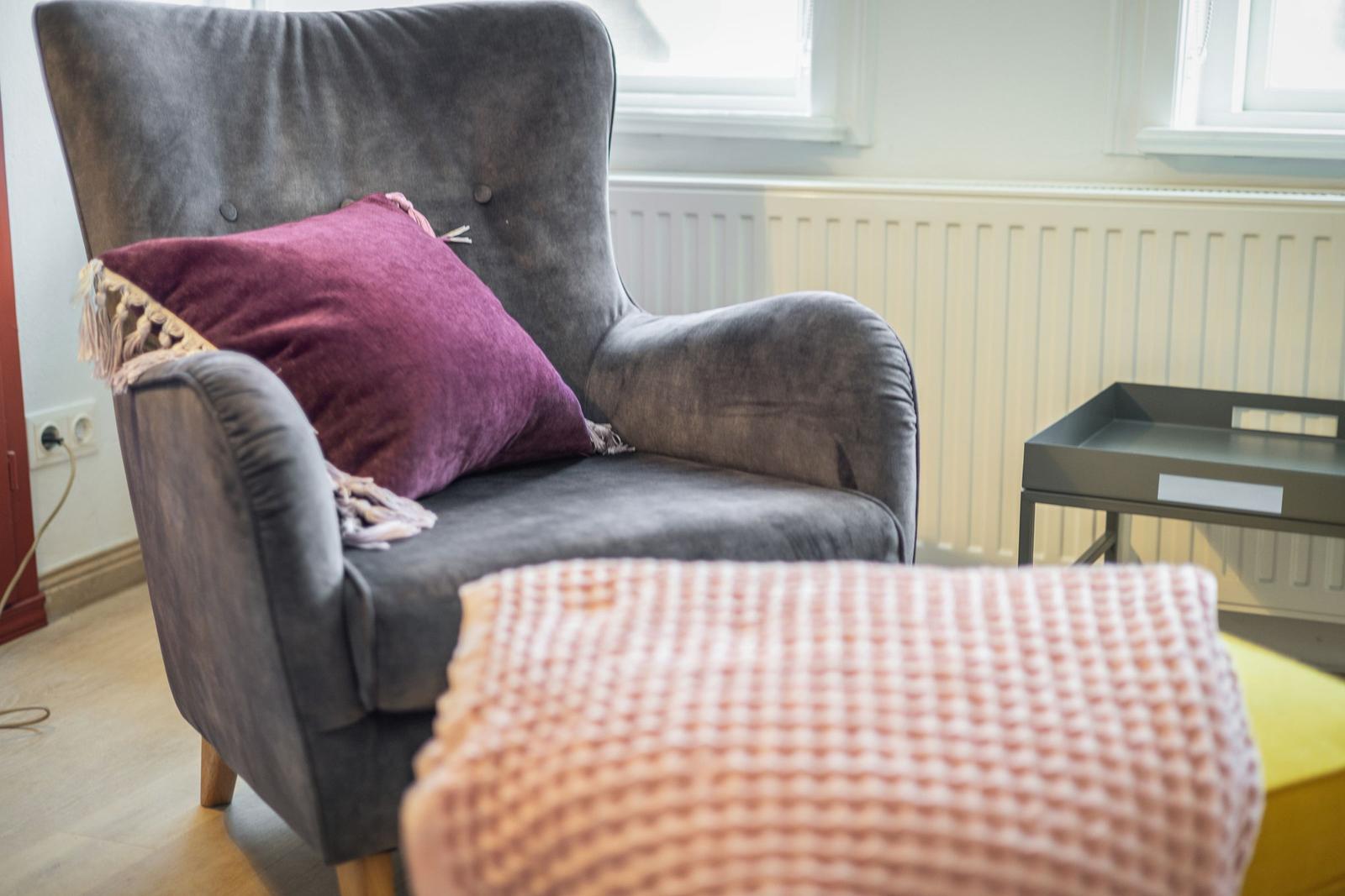 A gray armchair with a cushion and a side table.