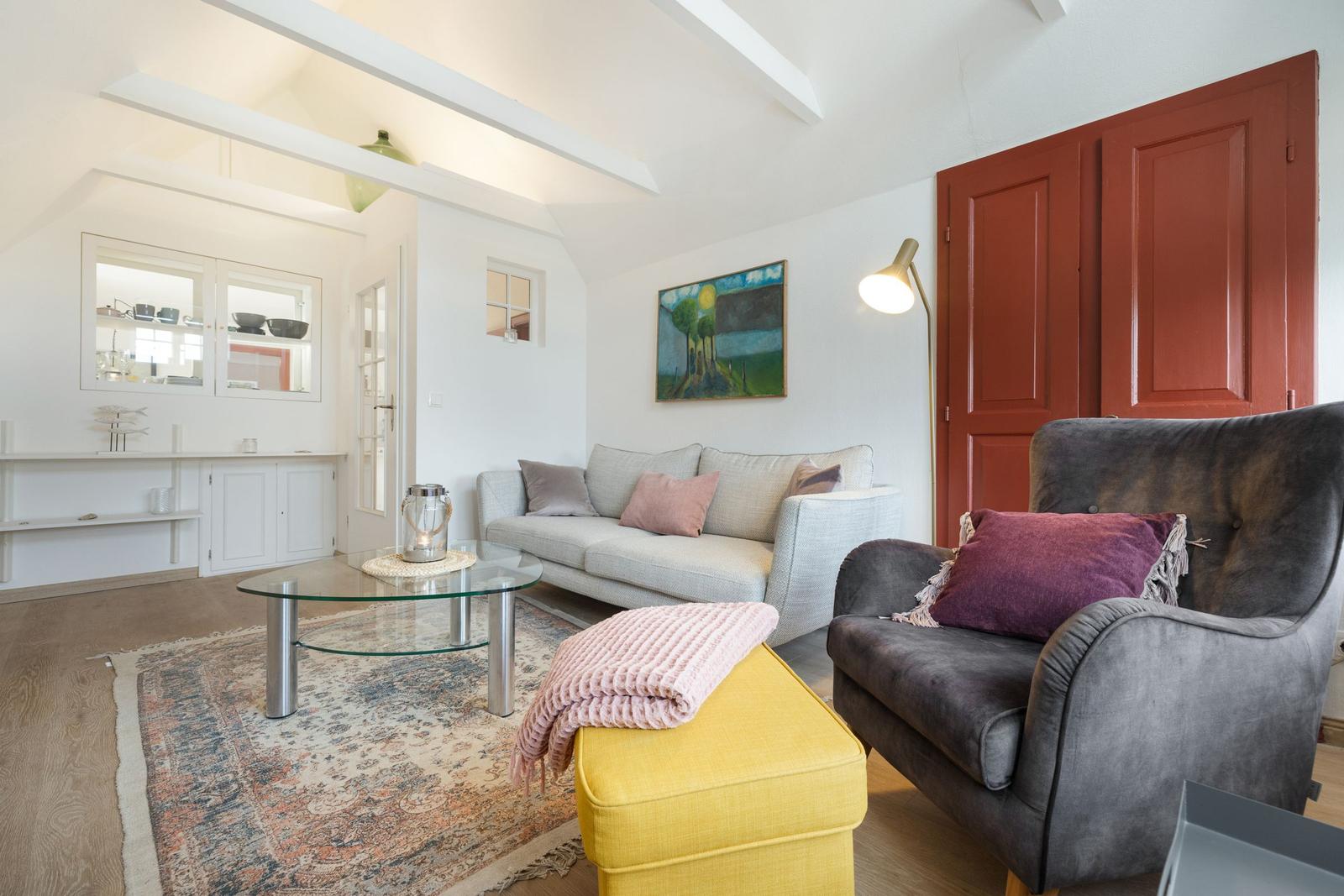 Living room with sofa, armchair, glass table, and rug.