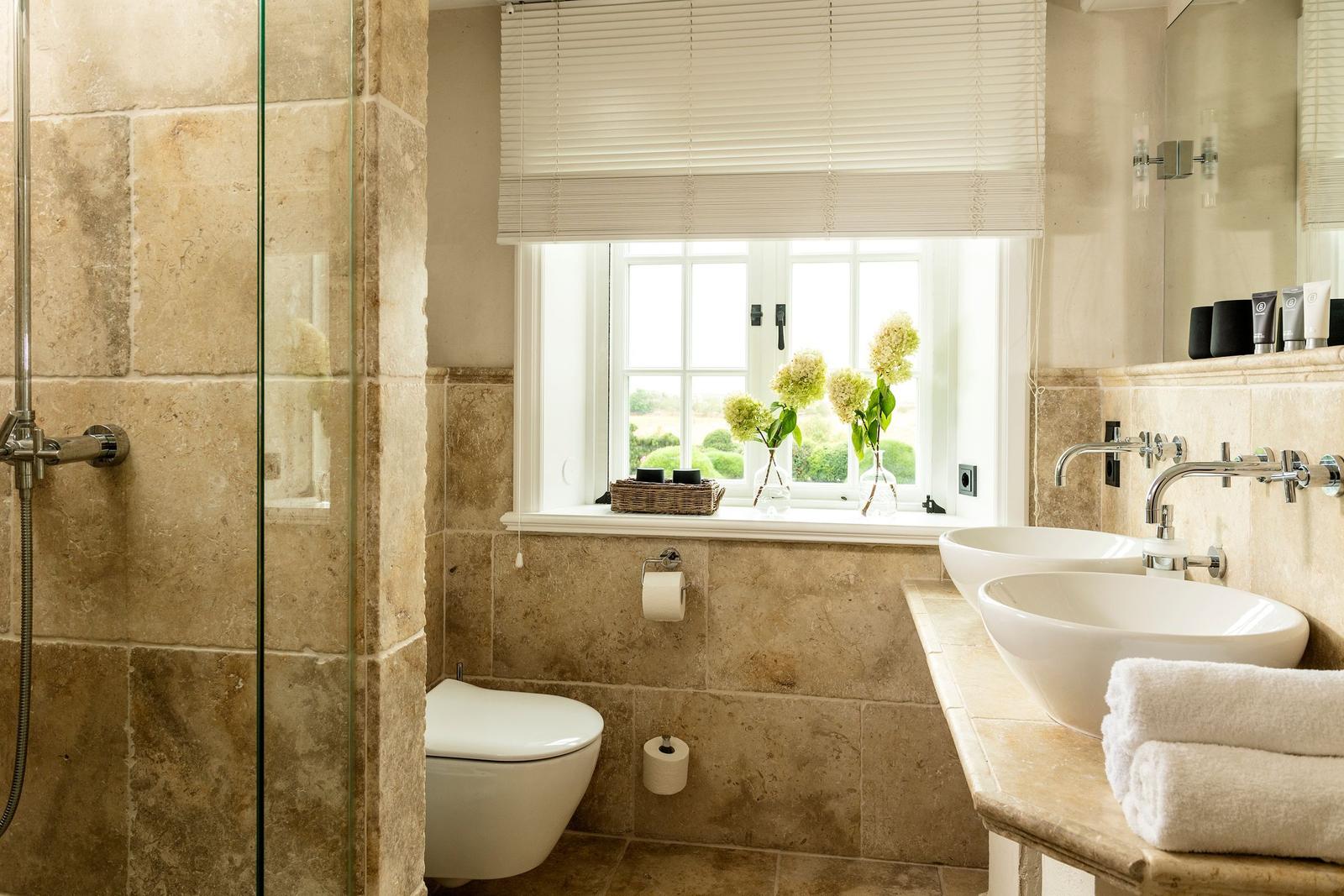 Badezimmer mit Dusche, Toilette und zwei Waschbecken