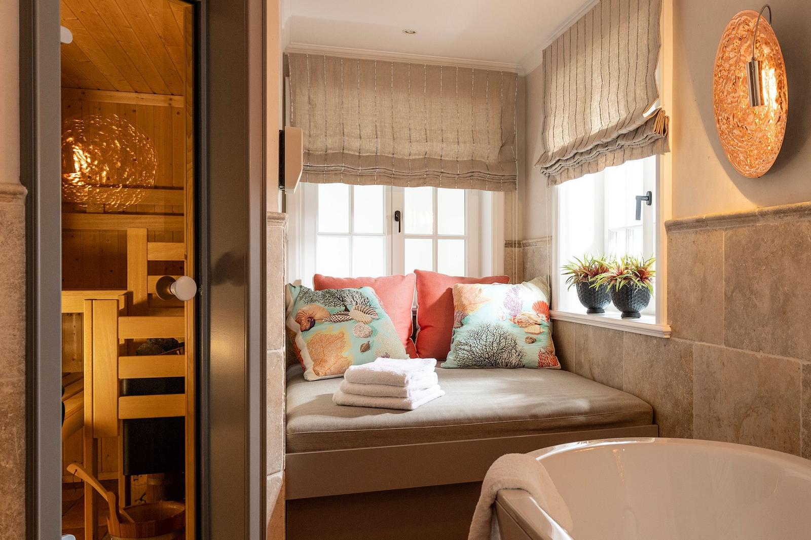 Dusche mit Sitzbank, Fenster und Sauna im Hintergrund.