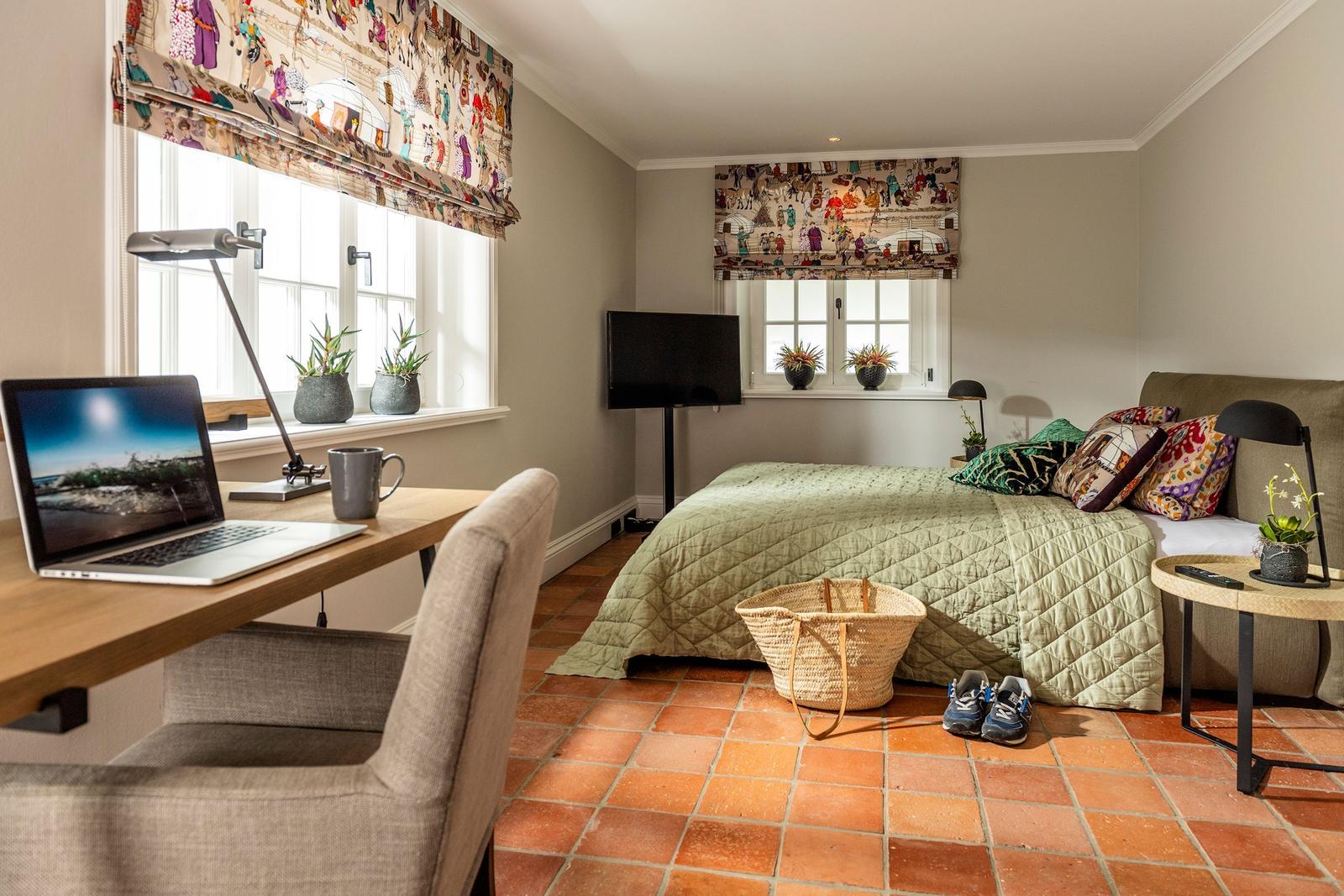 Schlafzimmer mit Arbeitsplatz, Bett und Terrakottboden