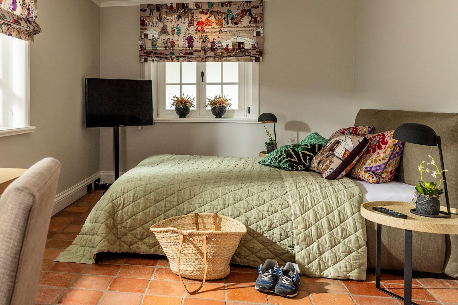Schlafzimmer mit Bett, Fenster, TV und Bodenfliesen
