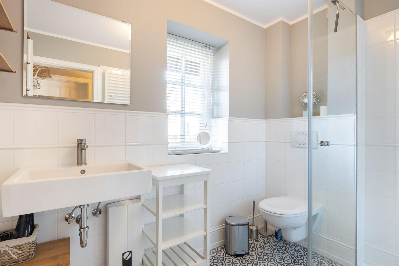 Bathroom with shower, sink, and toilet. Window with blinds.