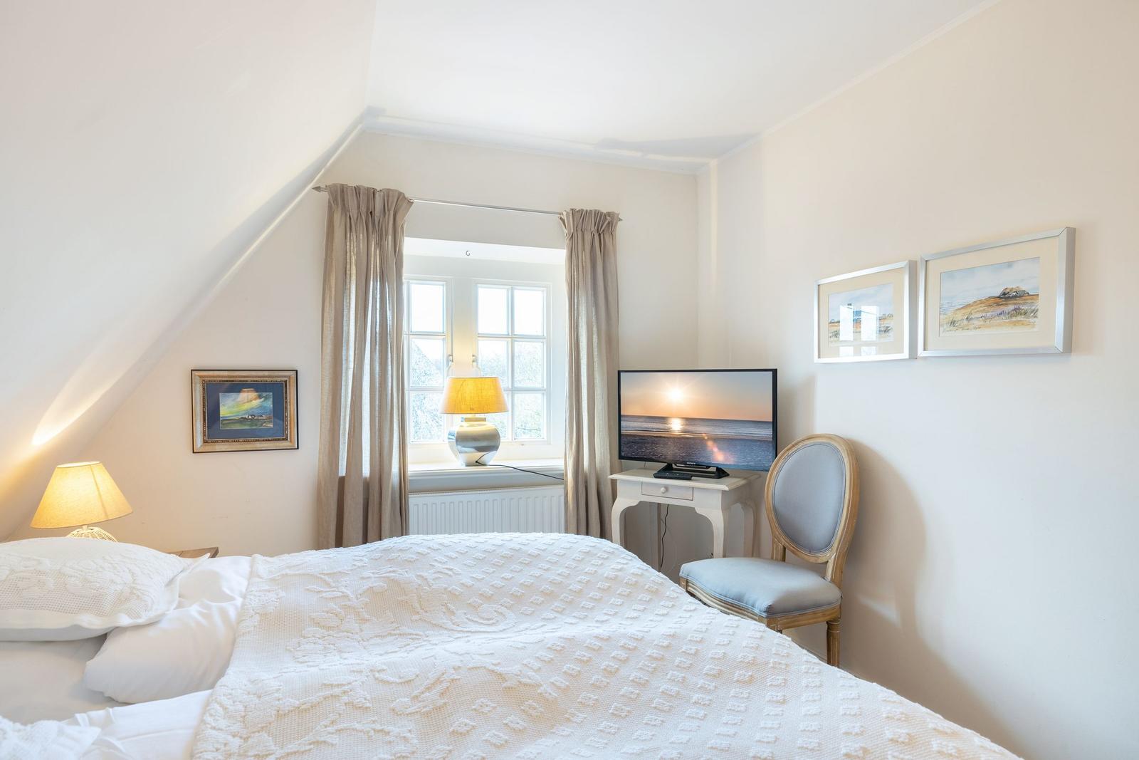 Bedroom with bed, window, TV, and chair.