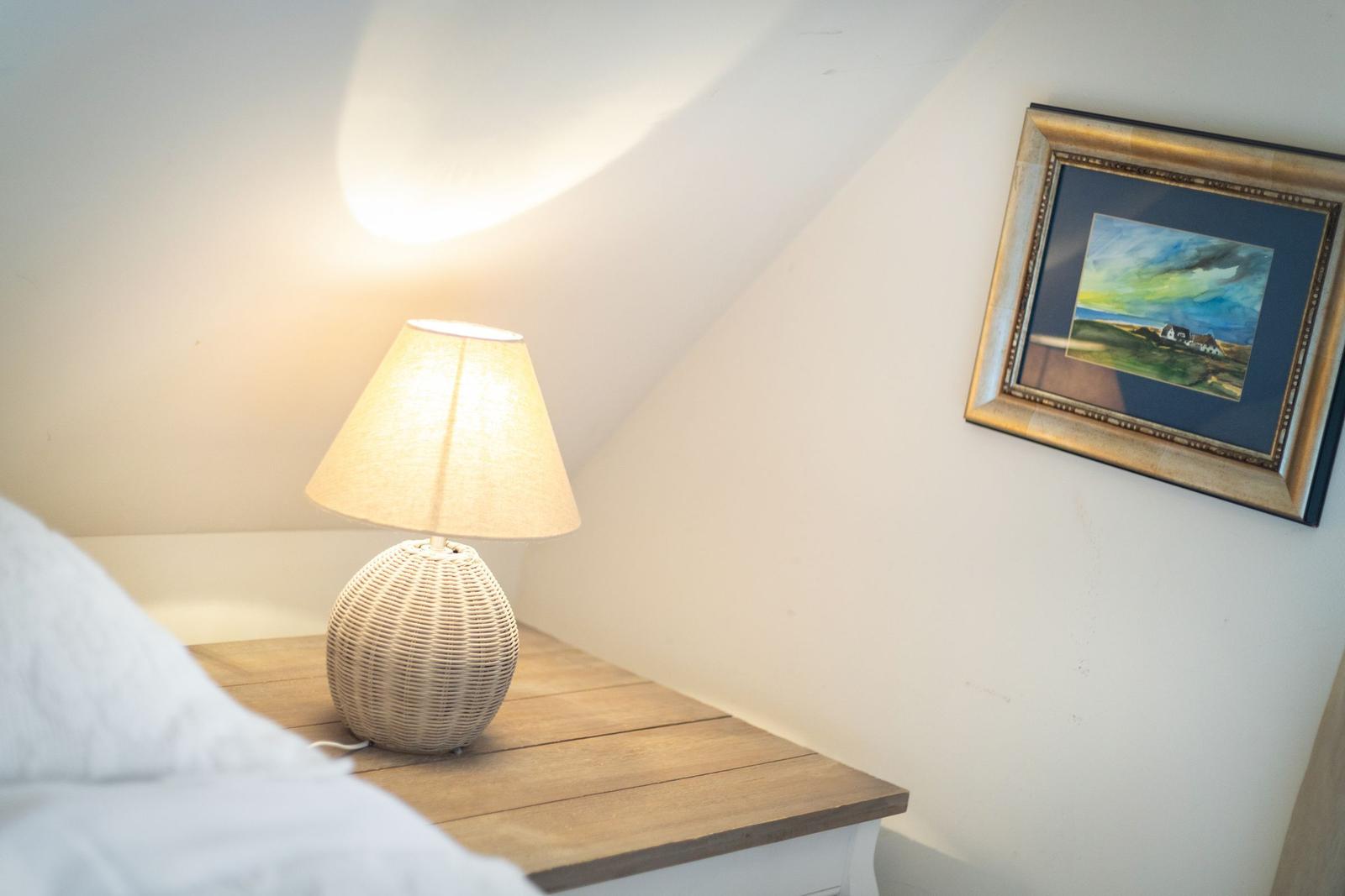 Bedroom with nightstand, lamp, and picture on the wall.