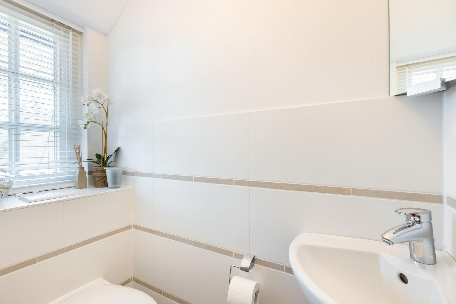 Bathroom with sink, toilet, and window with blinds.