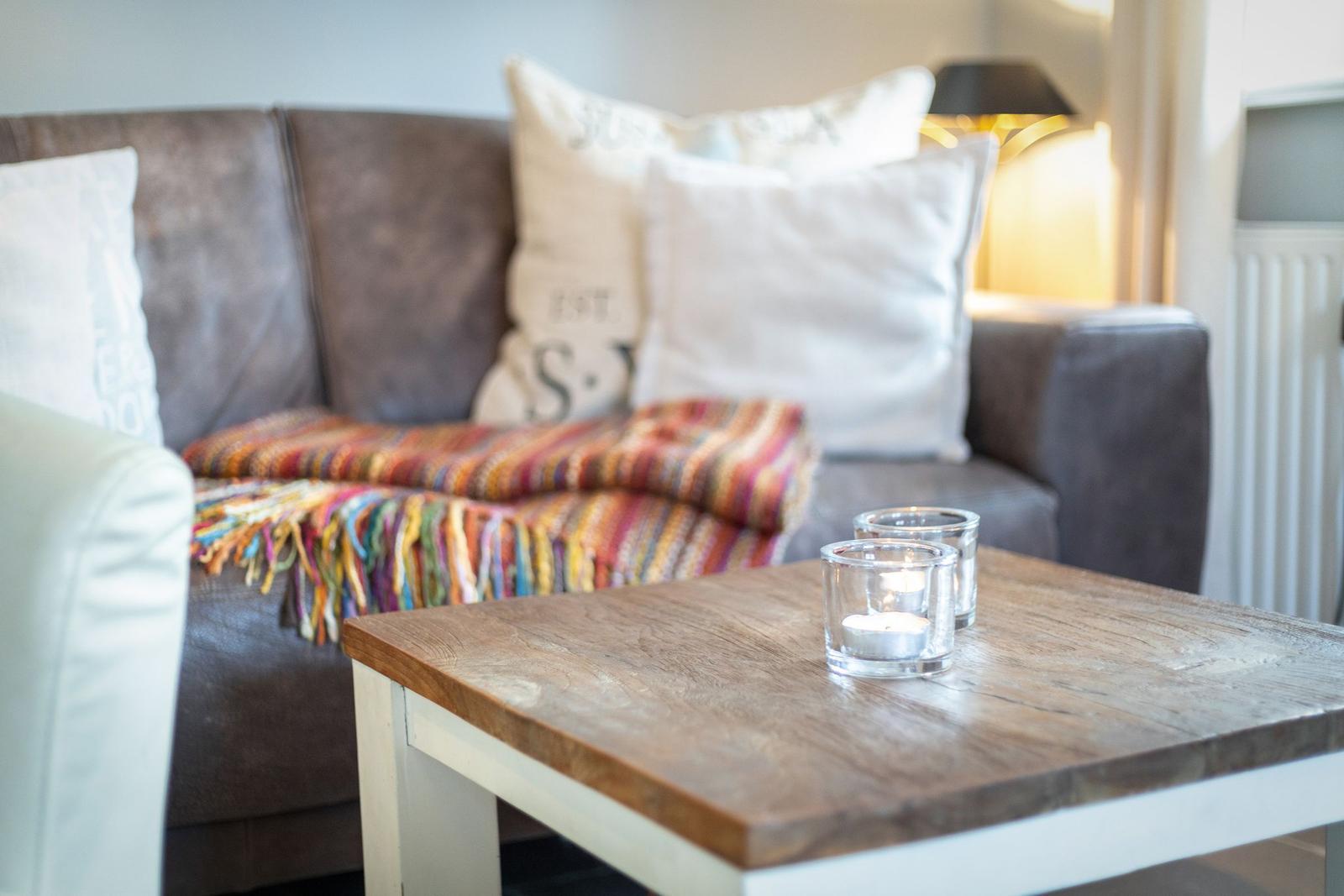 A living room with a sofa, a wooden table, and two tea lights.