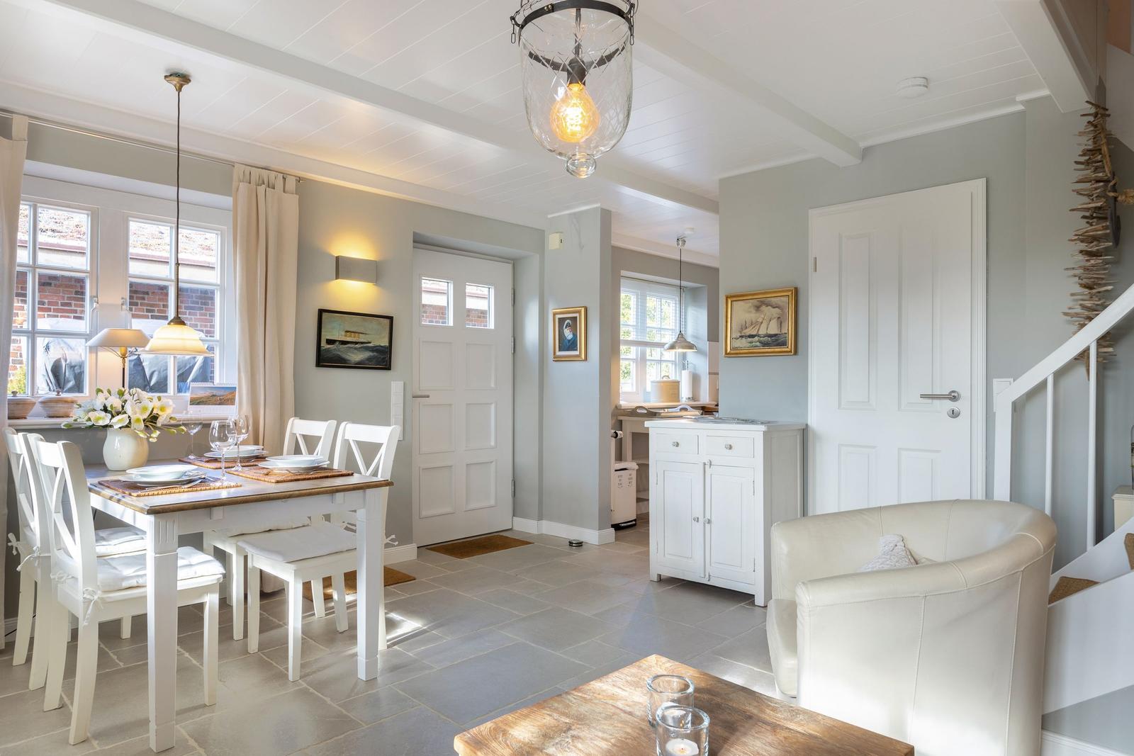 Dining area with table, chairs, and windows. Living area with sofa and kitchenette.