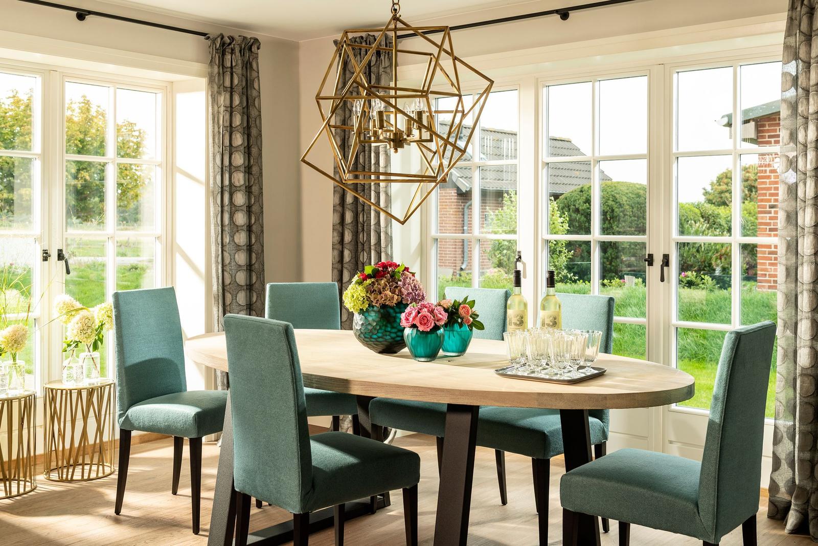 Esszimmer mit runden Tisch, sechs Stühlen und geometrischem Deckenleuchter.