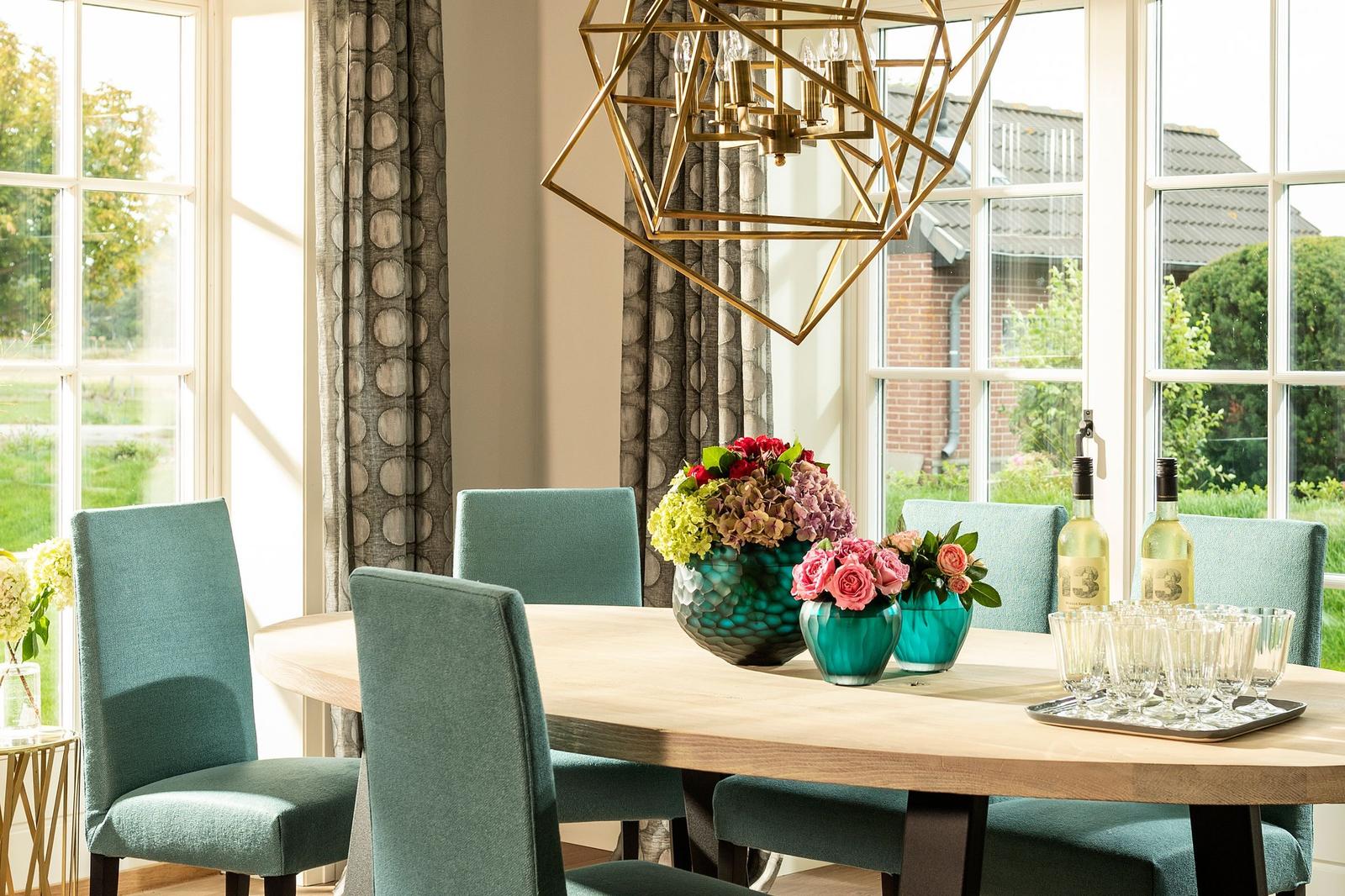 Esszimmer mit Holztisch, blauen Stühlen und Blumenvasen.