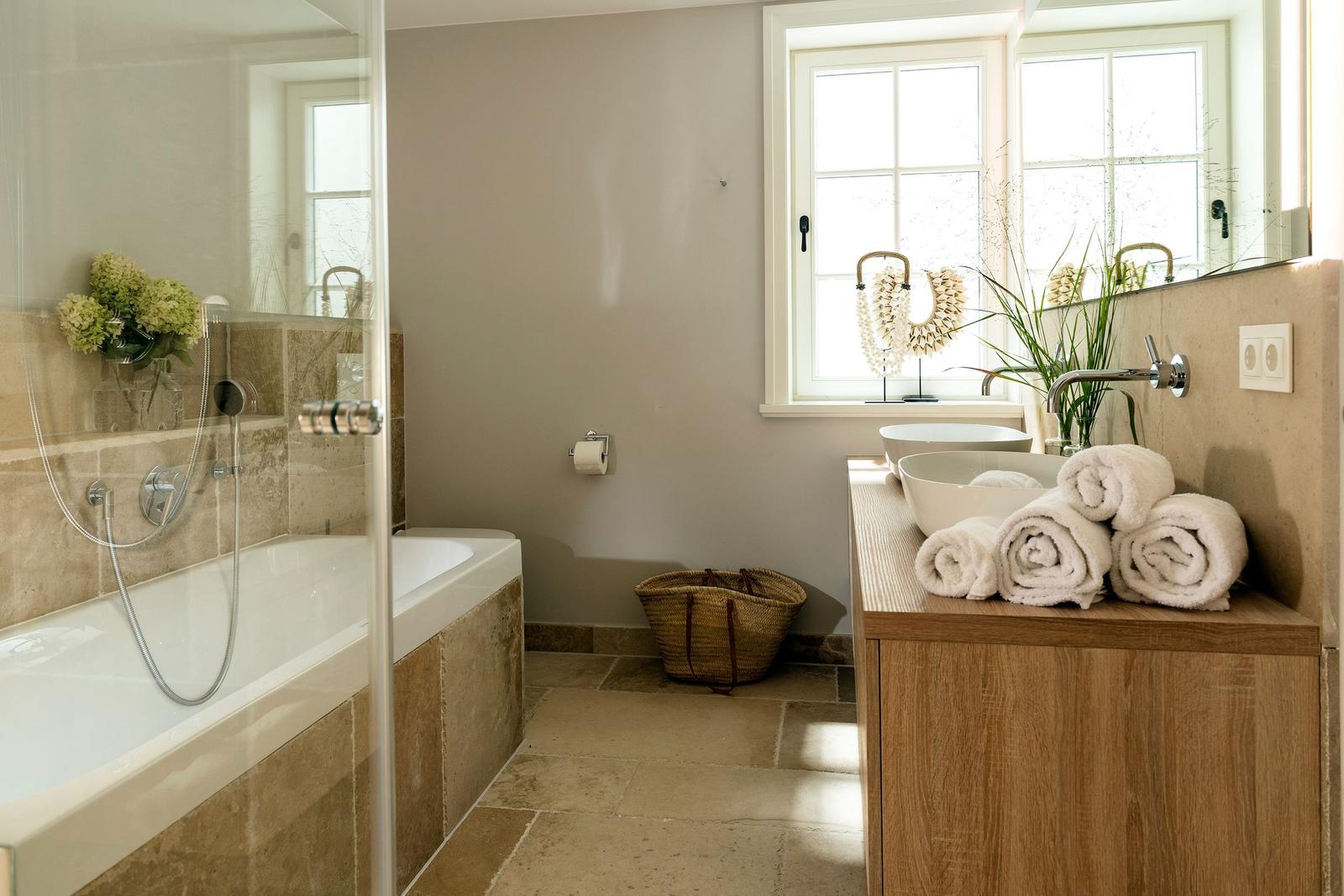 Bad mit Badewanne, Dusche, Waschbecken und Fenster.
