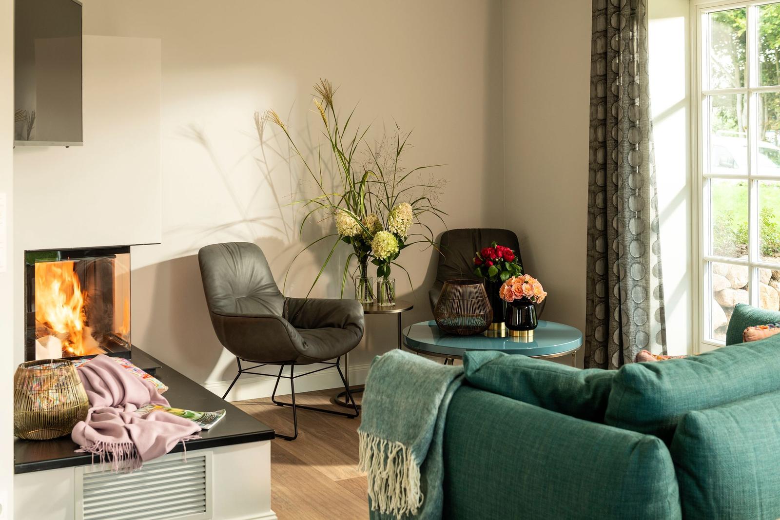 Ein Wohnzimmer mit Kamin, Sitzgelegenheiten und Blumen.