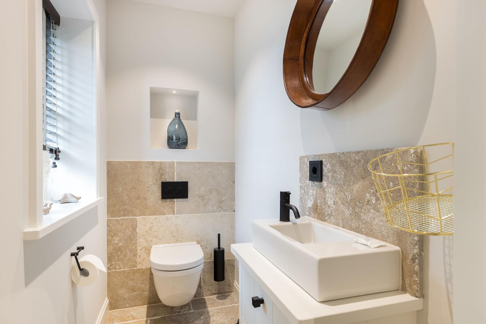 Badezimmer mit Waschbecken, Spiegel und Toilette