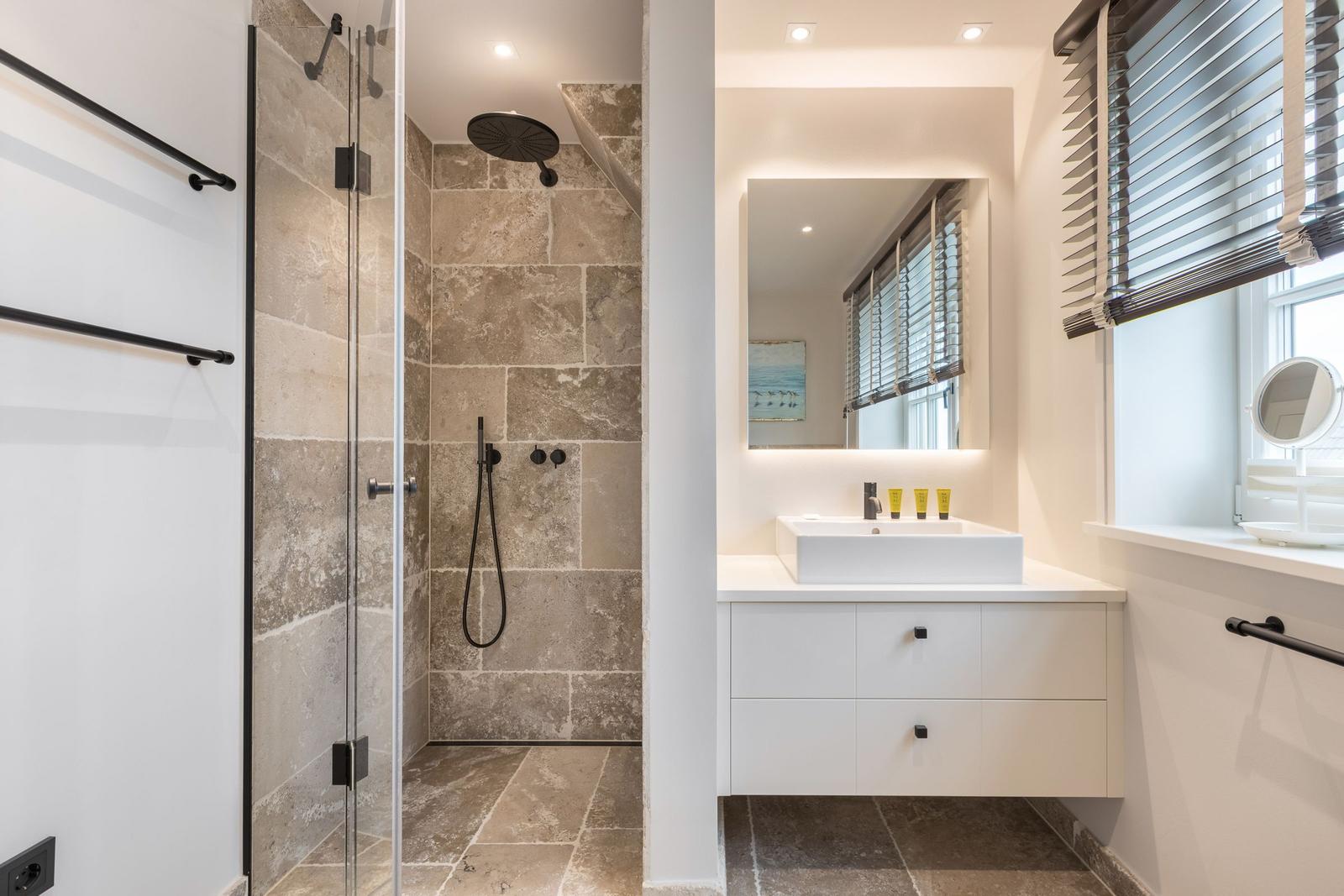 Dusche mit Steinwand und Waschbecken mit Spiegel
