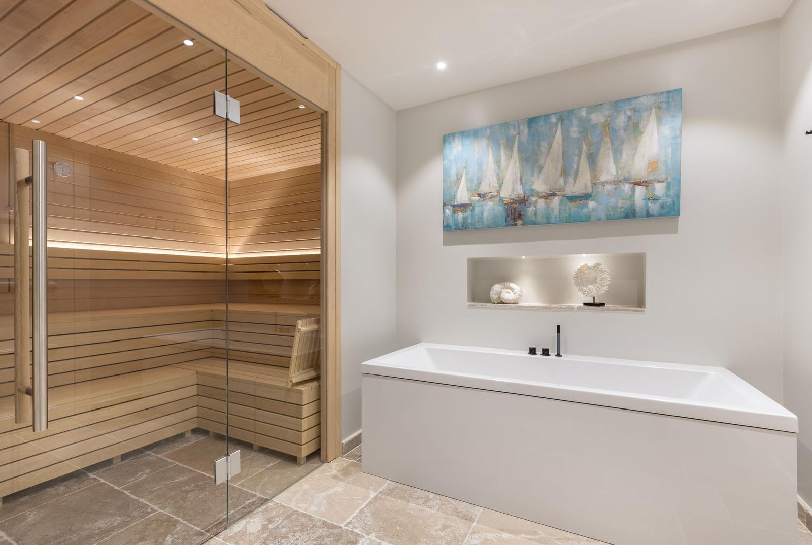 Dusche mit Holzsauna und Badewanne mit Wandbild.