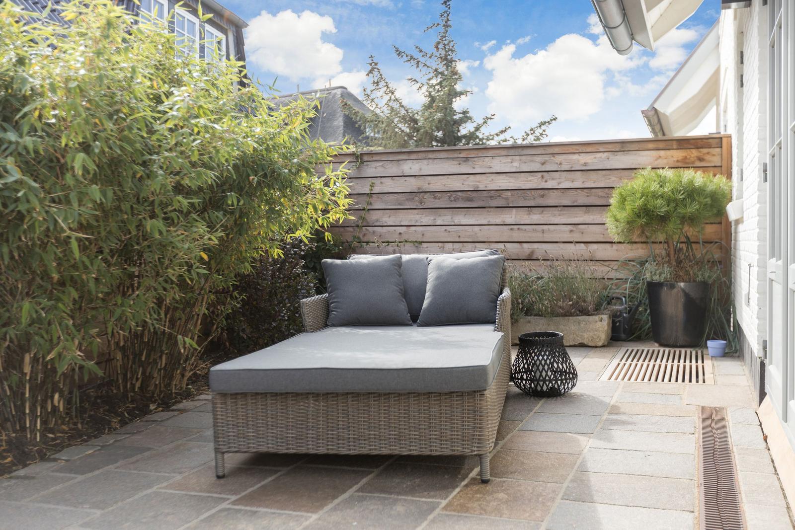 Terrasse mit Liege, Pflanzen und Holzgeländer