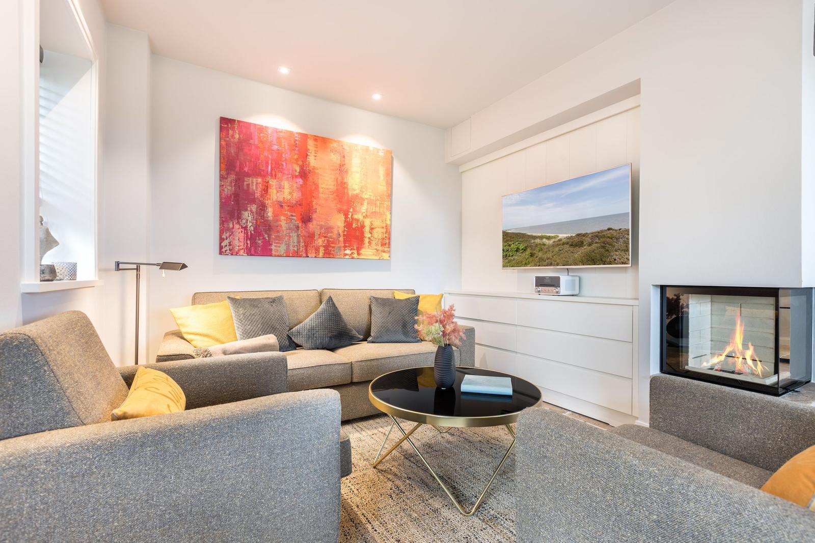 Wohnzimmer mit Sofa, Kamin und Fernseher an der Wand.