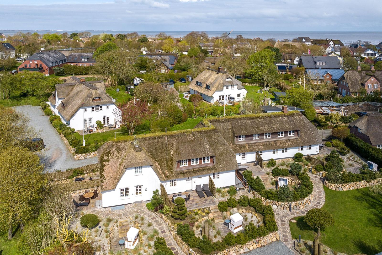 House with thatched roof and garden, view of coastal landscape.