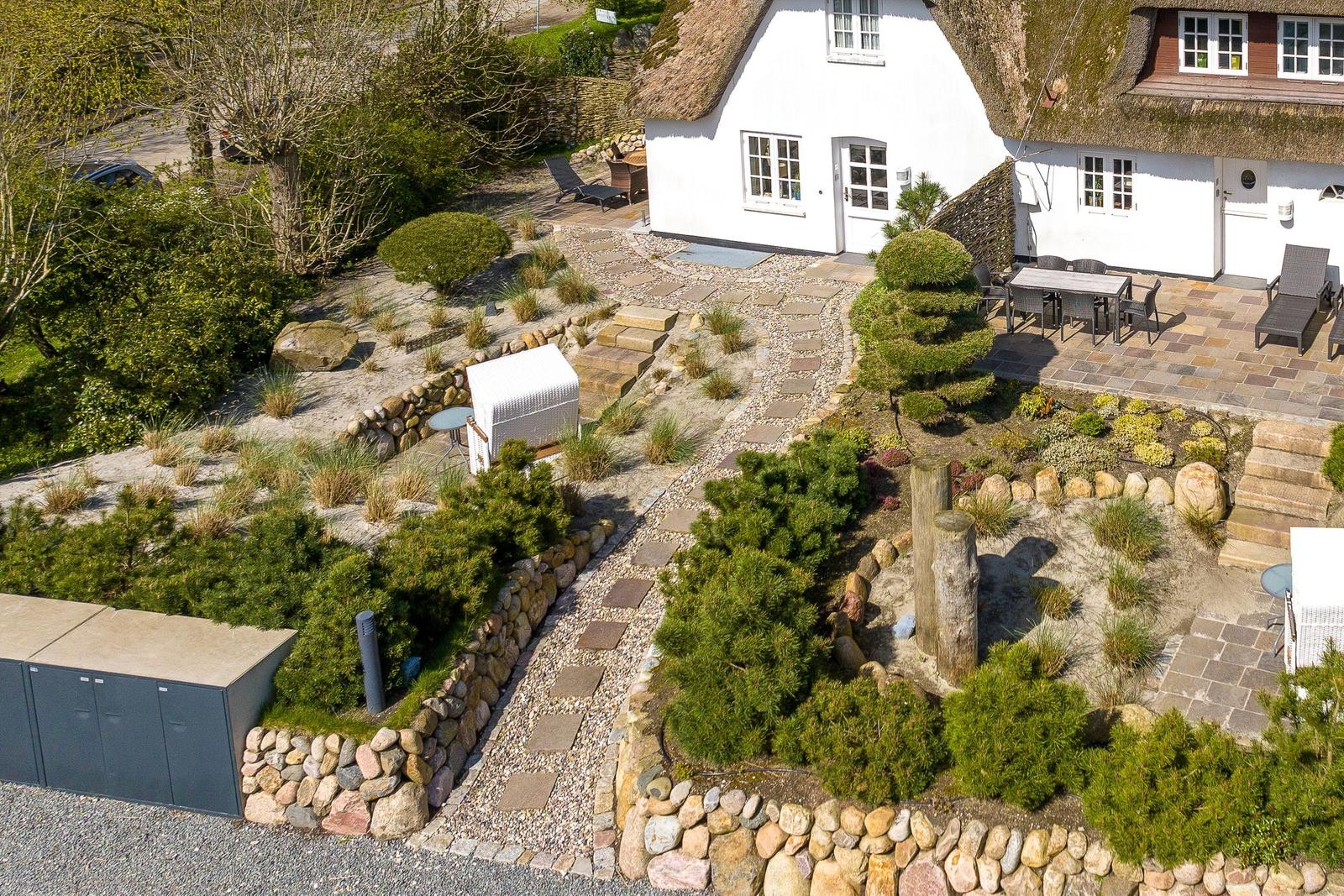 House with thatched roof, paved garden and stone path.