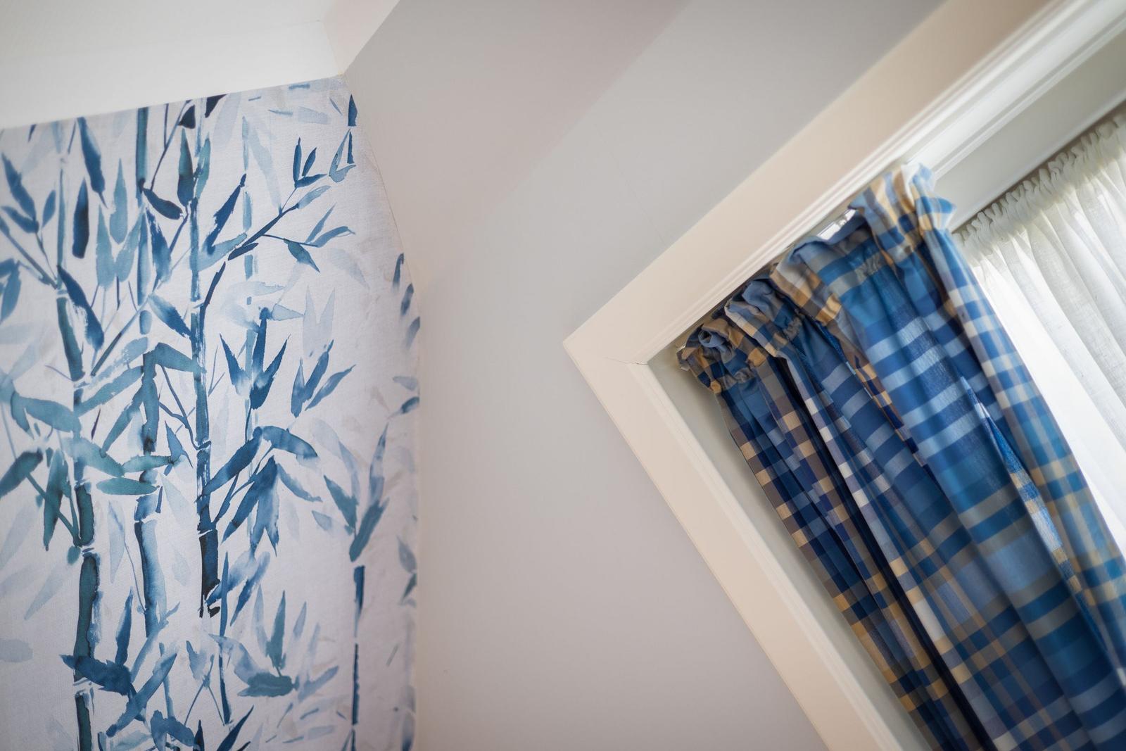 Wall with bamboo pattern and blue checkered curtains at a window.