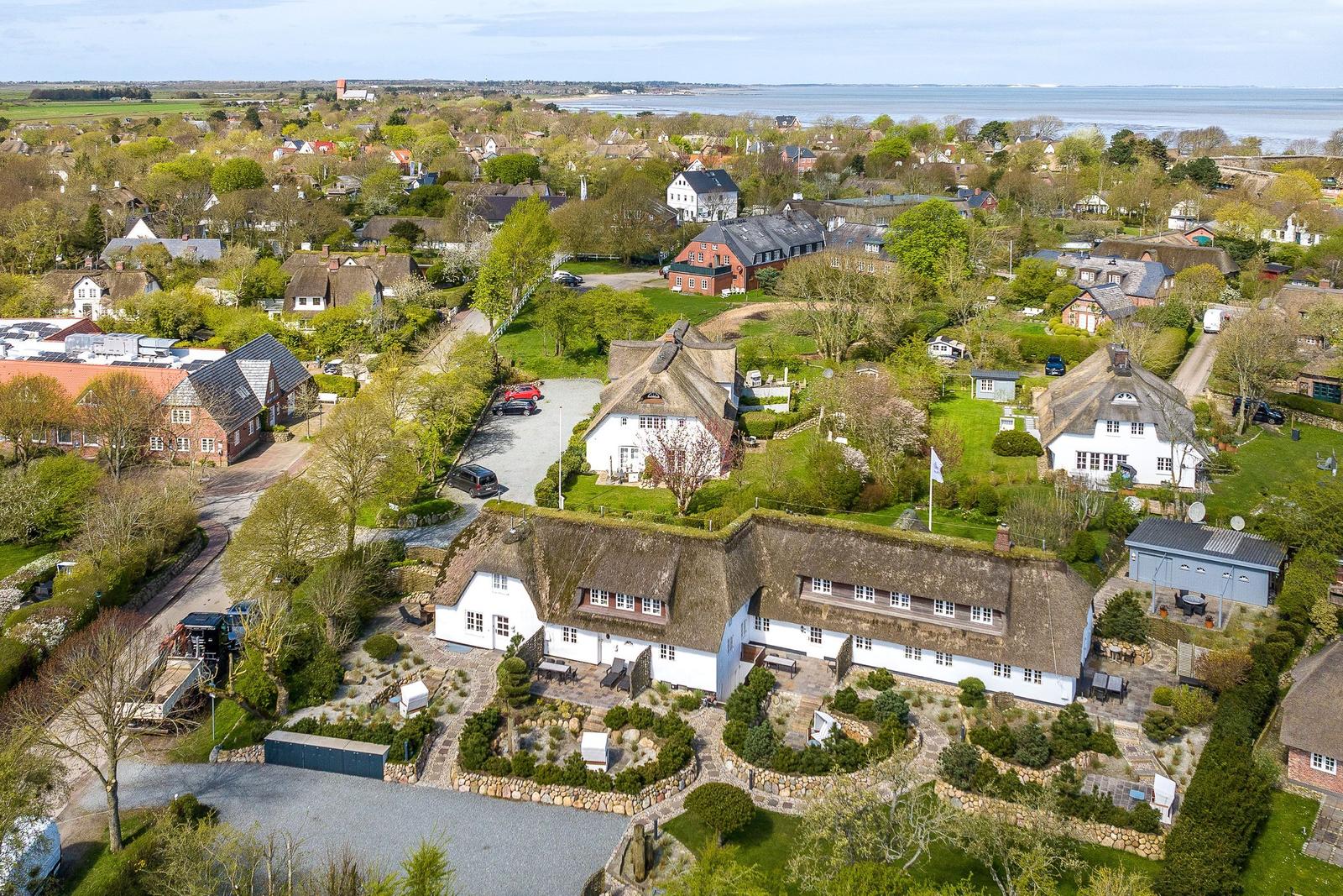 House with thatched roof and garden. View of the village and the lake.