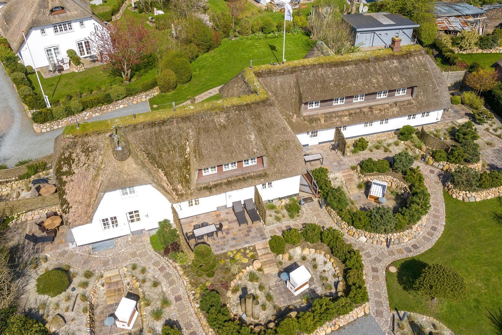 Farmhouse with thatched roof and landscaped garden area.