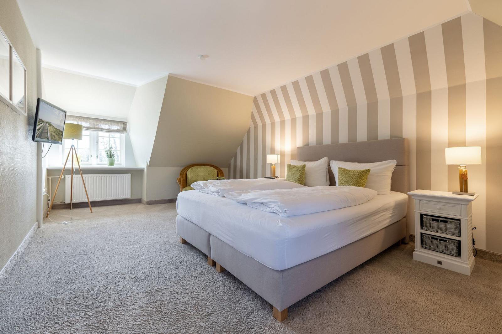 Bedroom with bed, nightstand, and TV mounted on the wall.