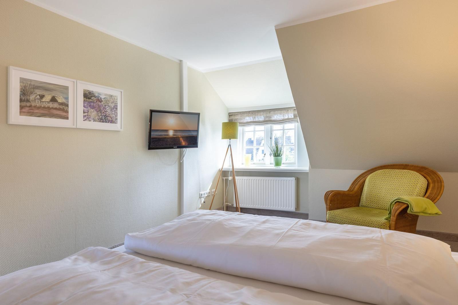 Bedroom with bed, TV, chair, and window.