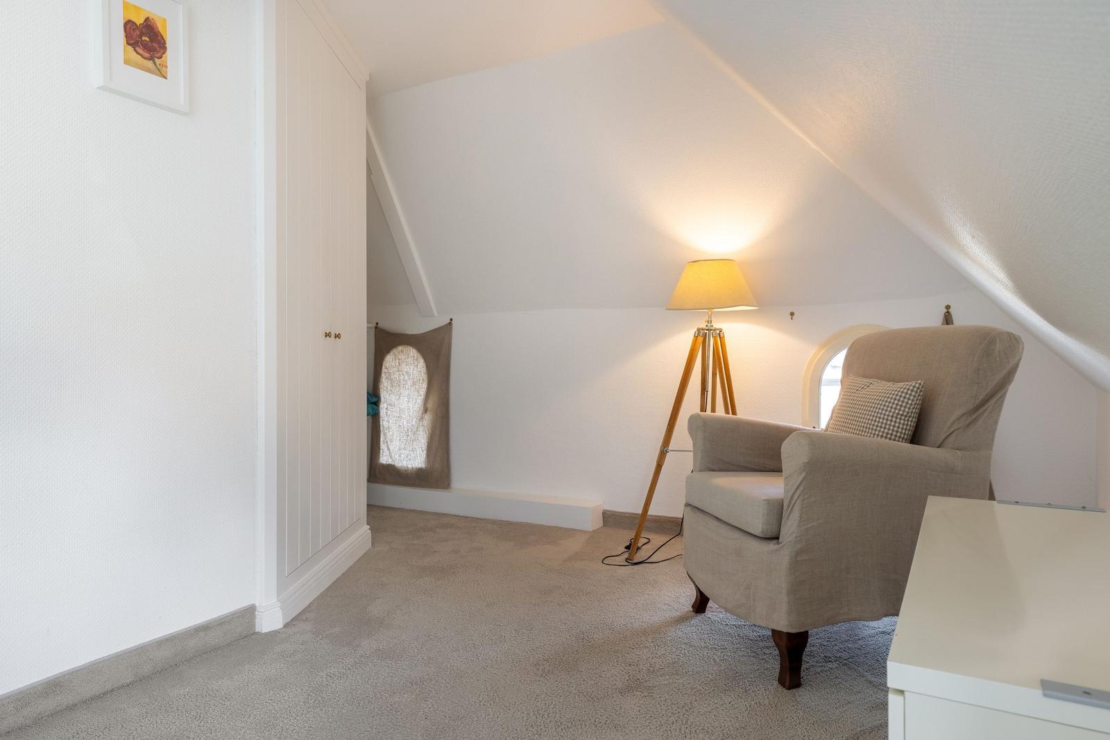 Attic room with armchair, floor lamp, and wardrobe.