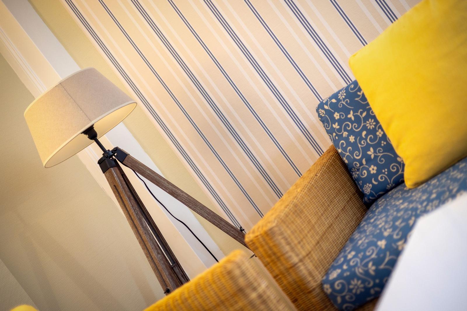 Sofa with cushions and floor lamp against striped wall