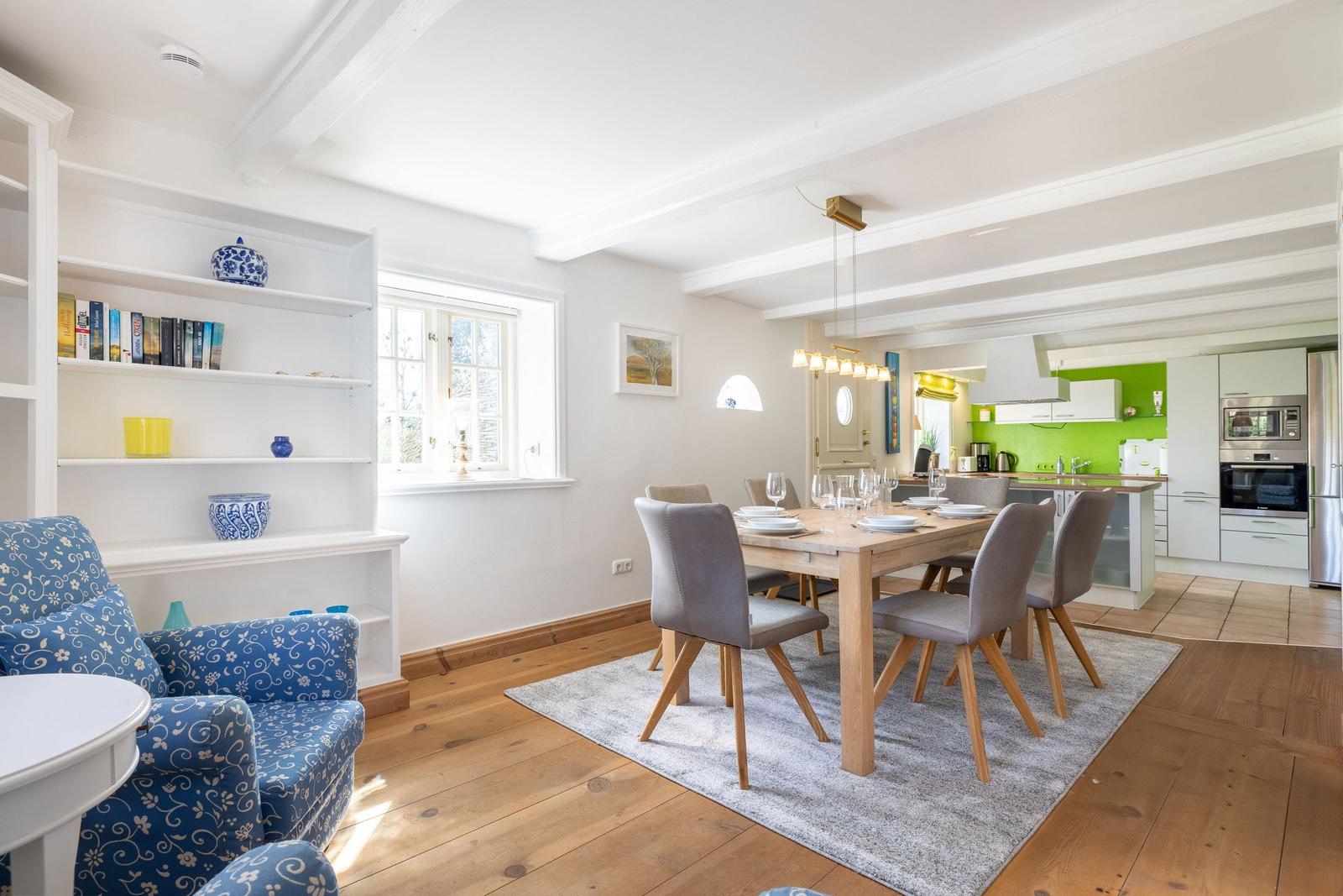 Dining room with wooden table, chairs, and view into kitchen