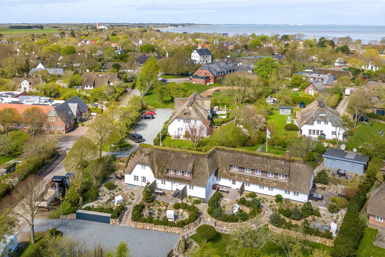 House with thatched roof, garden, and view of the water