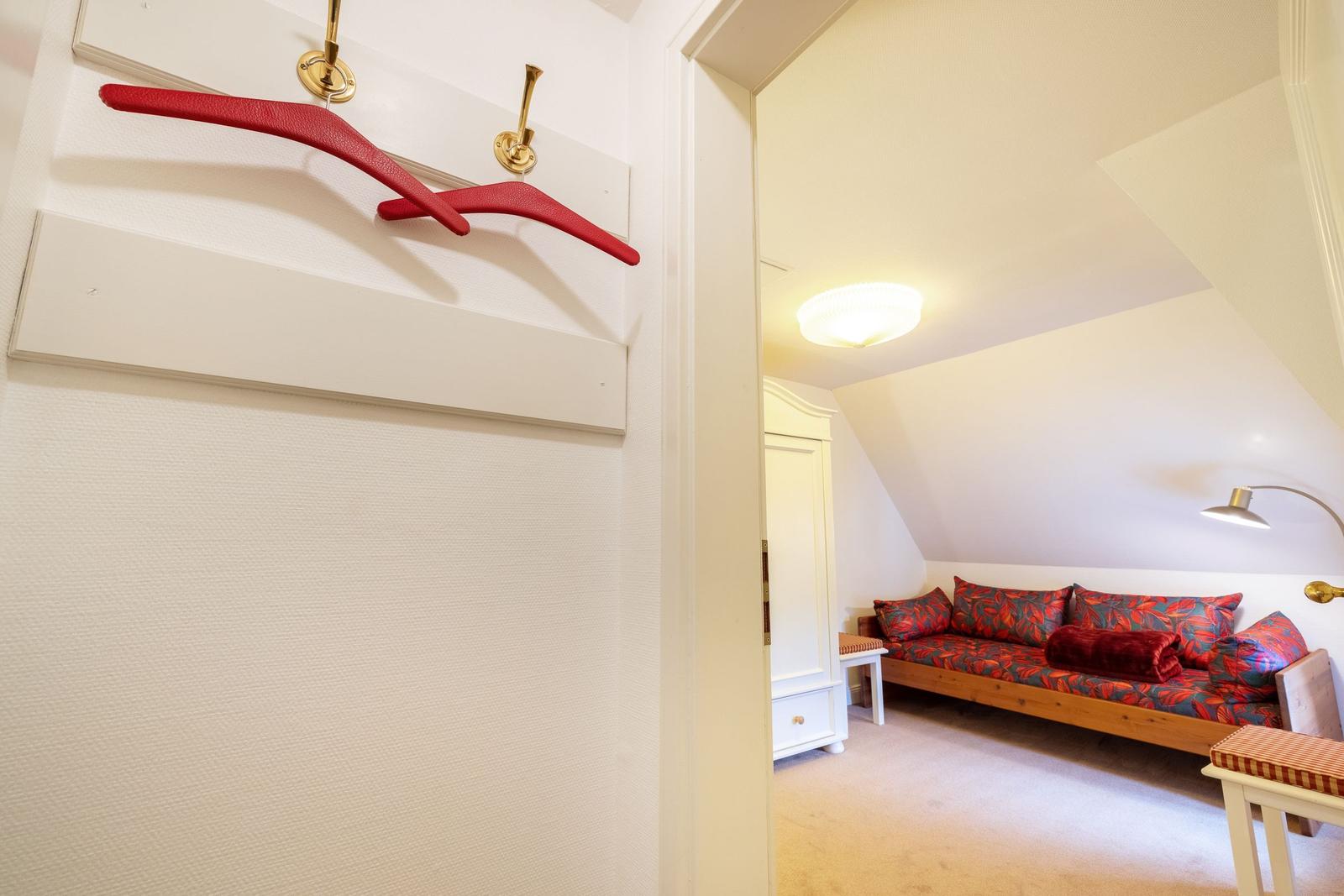 Bedroom with sofa and coat hooks on the wall