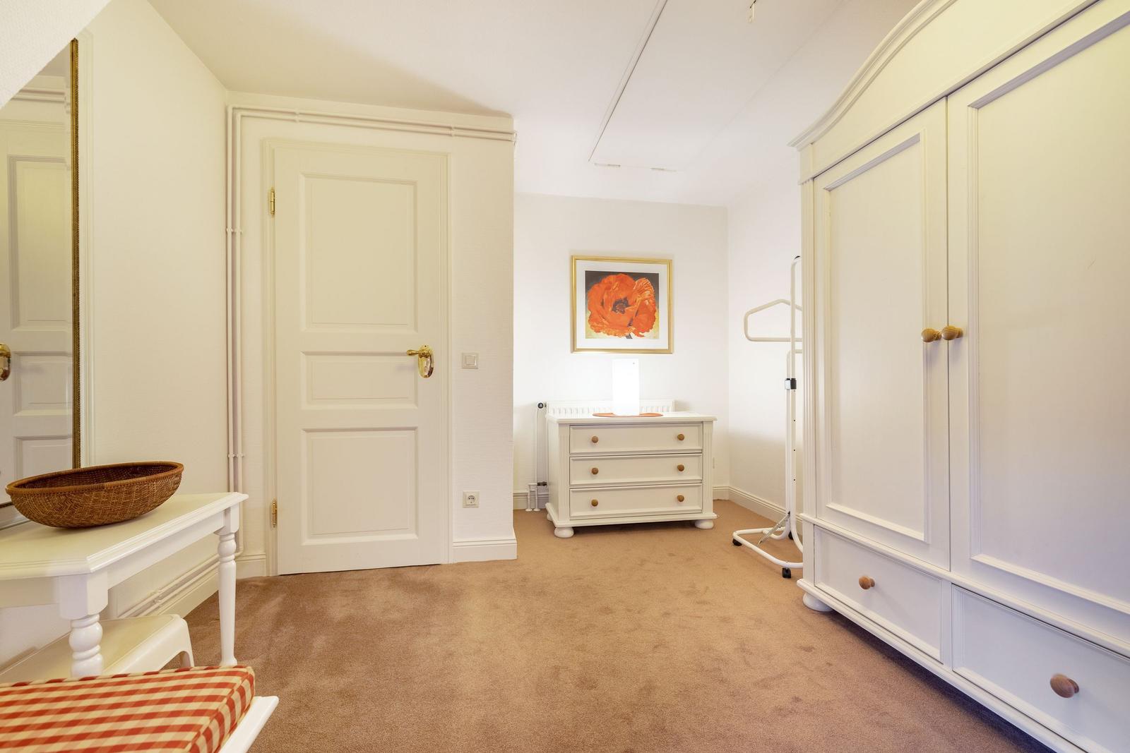 Bedroom with wardrobe, vanity table, and wall picture.