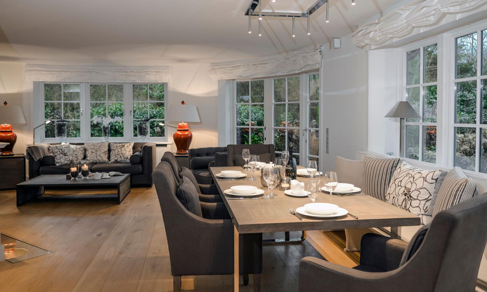 Esszimmer mit Tisch und Stühlen. Wohnbereich mit Sofa und Fenstern.